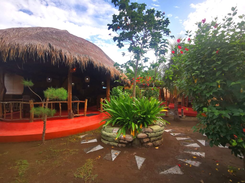 Thatched open-air lounge and tropical garden at Kampung Meno Bungalows on Gili Meno