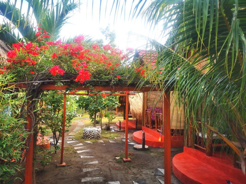 Garden path under red bougainvillea between the bungalows at Kampung Meno Bungalows