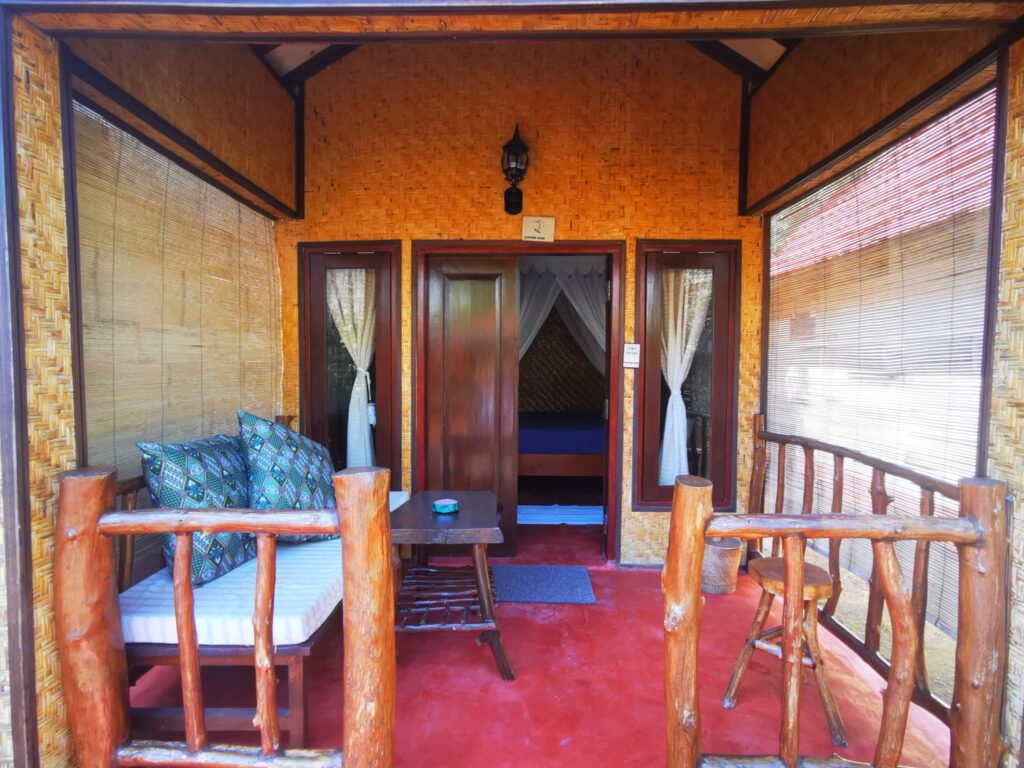 Private verandah with a daybed outside a bungalow at Kampung Meno Bungalows